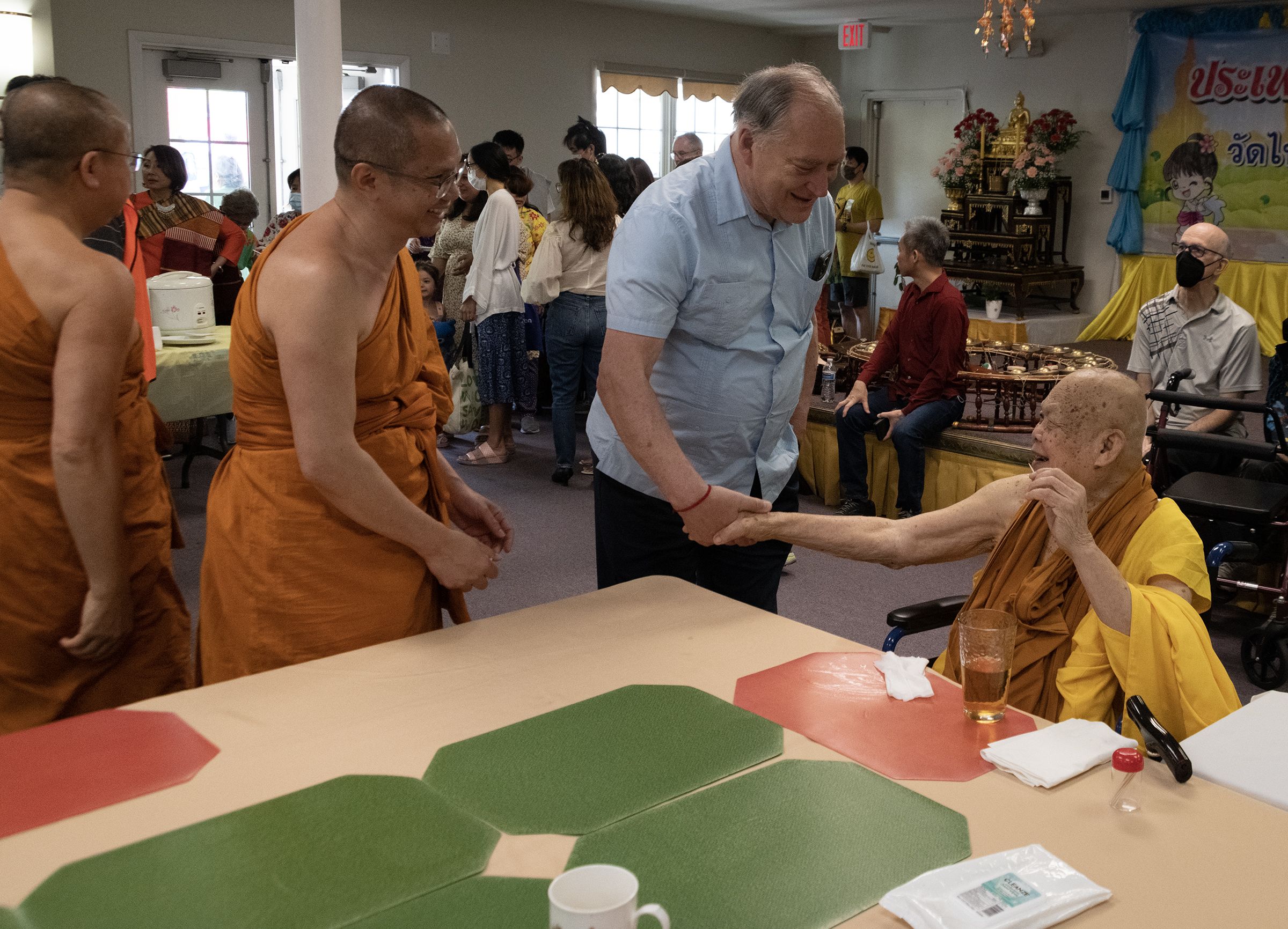 County Executive Marc Elrich shakes hand of monk in saffron robes.