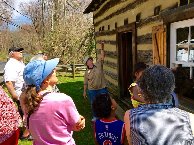 People listening to a tour guide outside Oakley Cabin